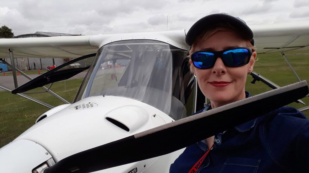 Charlotte outside in a field in front of a light aircraft